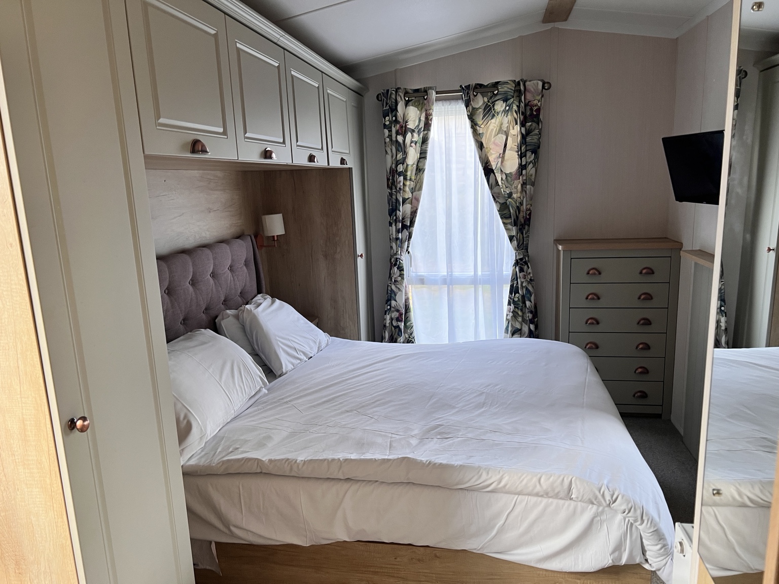 Double bedroom with white bedding and built-in storage at Devon Cliffs