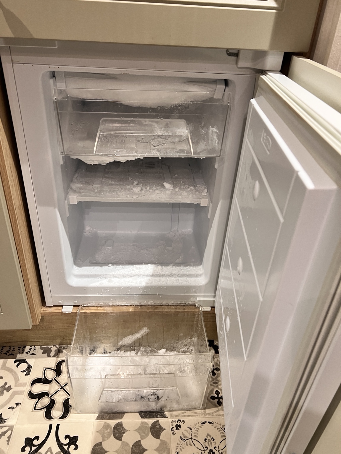 Open freezer heavily coated in ice with the freezer drawer removed