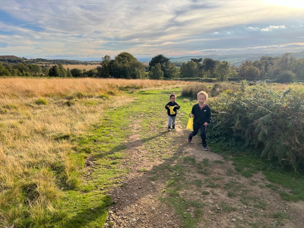 Oscar and Casey walking along a path through grassy fields at Longshaw Estate.