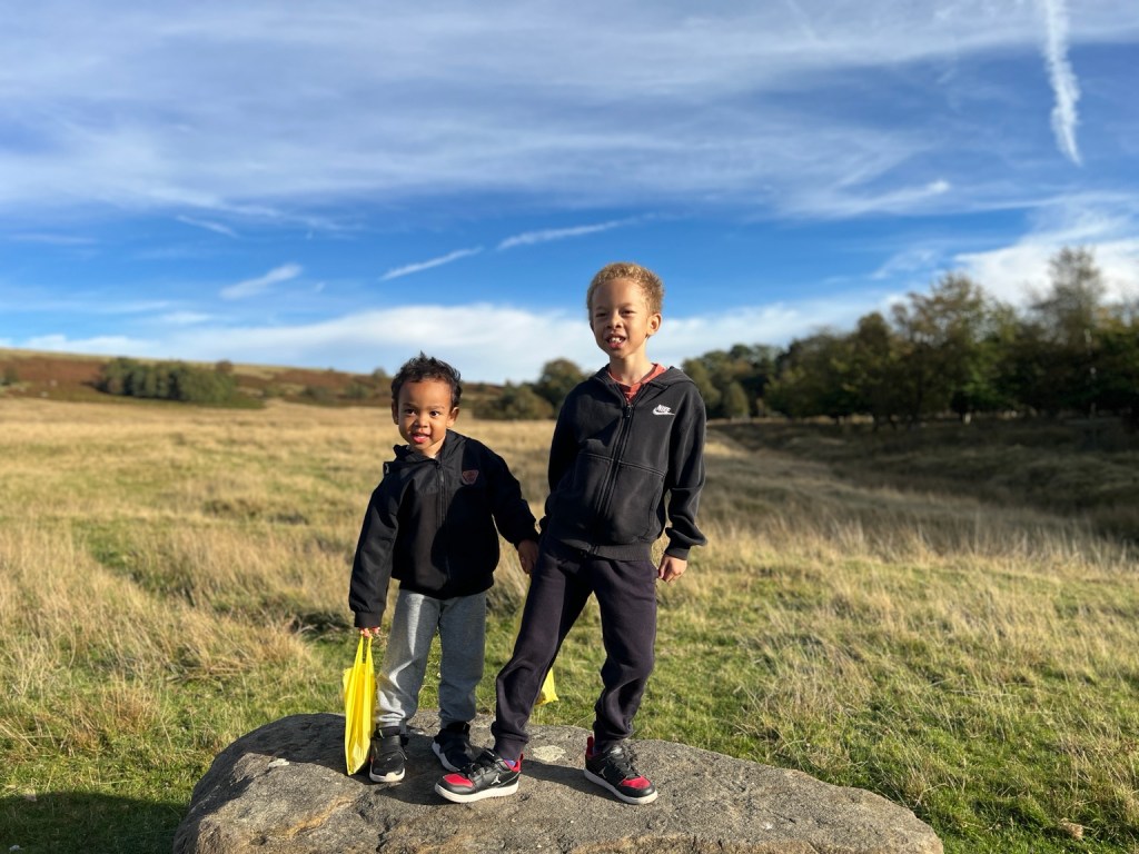 Oscar and Casey standing together on a rock in an open field at Longshaw Estate.