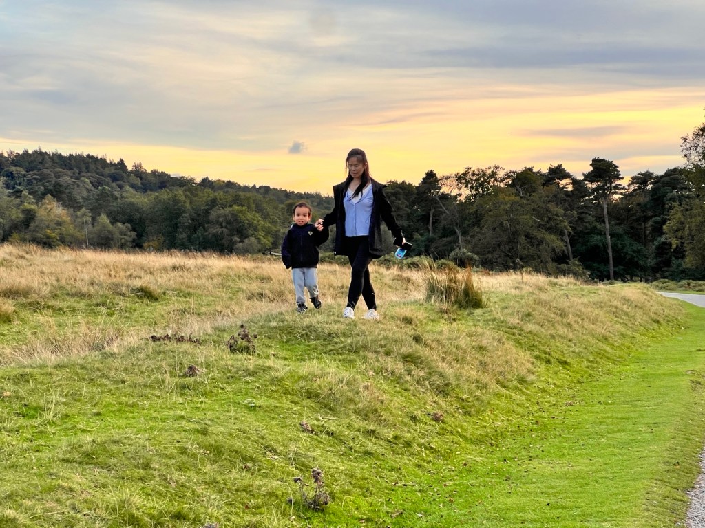 Grandma and Casey walking together beside an open field in the evening at Longshaw Estate.